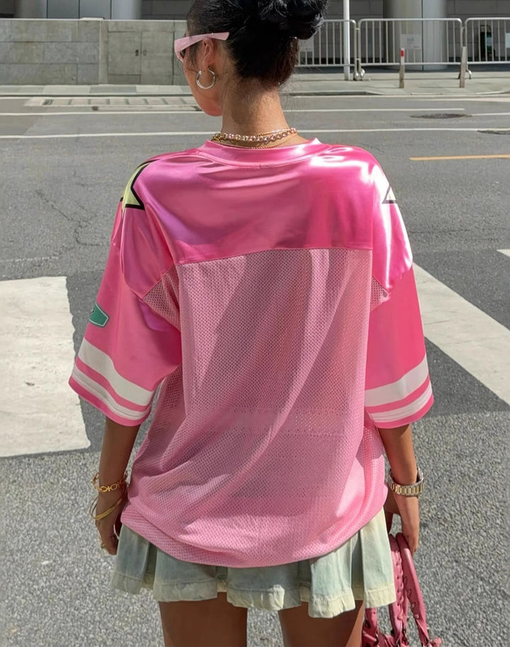 Model wearing a pink oversized jersey with mesh back panel, sporty striped sleeves, and a relaxed fit. A must-have for kawaii and Y2K aesthetic lovers.