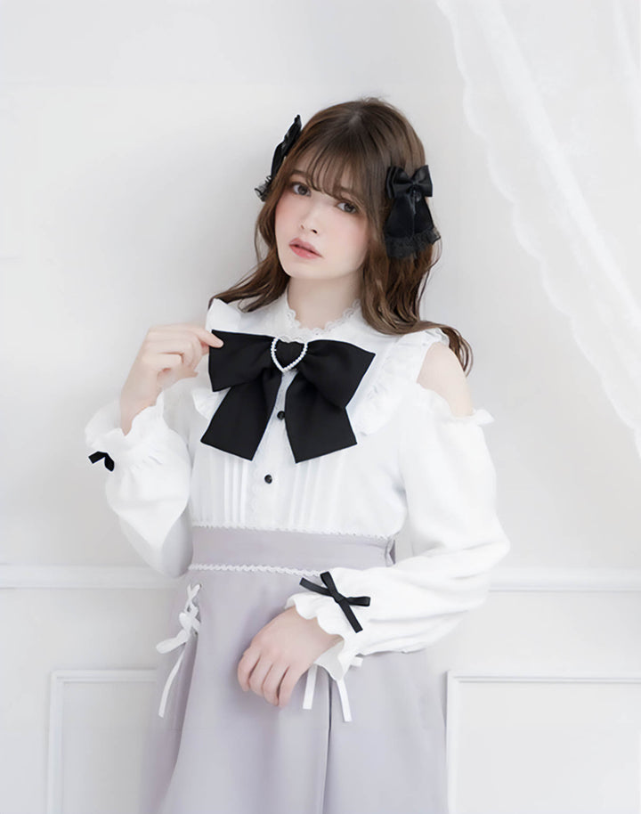 Model wearing a kawaii gothic blouse with off-shoulder design, adorned with a black bow, in a natural, versatile white color for goth fashion lovers.