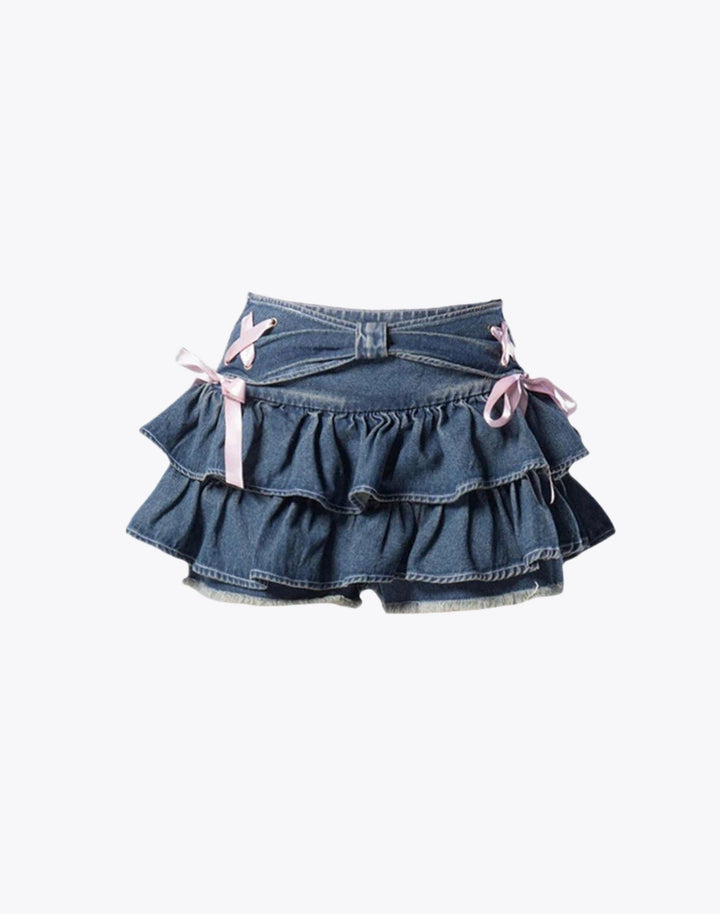 Flat lay of the Mini Denim Ruffle Skirt showing the front details, including the pink ribbon bows and the ruffled layers.