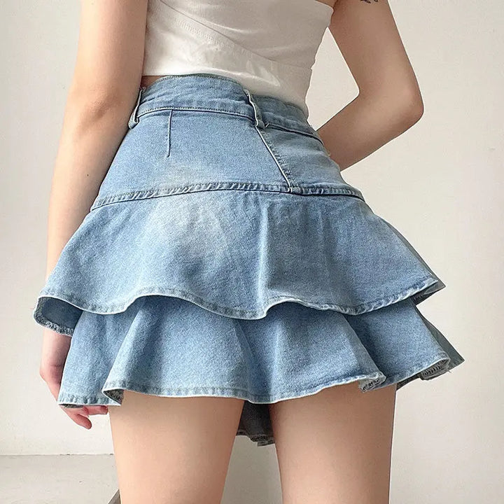 Back view of a Y2K denim ruffle skirt featuring a light blue wash, visible stitching, and a fitted waistband with playful dual-layered ruffles.