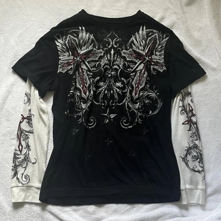 Flat-lay of black and white gothic t-shirt with layered sleeves, showing cross and wing graphics, styled for an alternative or emo look.